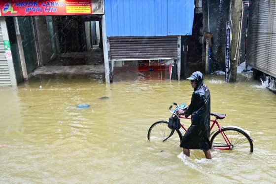 A resident wades through a flooded street after heavy rains in Malwana Town.jpeg