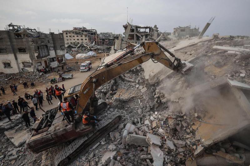 12月6日，在加沙中部布雷吉难民营，民防人员使用挖掘机在被毁建筑物的废墟中搜寻遇难者遗骸.jpg